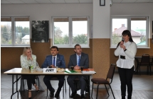 Kobieta mowiaca przez mikrofon, dwoje mezczyzn i kobieta przy stole