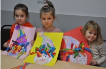 Trzy dziewczynki prezentujące swoje obrazki 