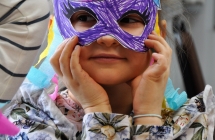 Dziewczynka trzymająca przy twarzy maskę karnawałową 