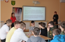 Dwie kobiety przy tablicy multimedialnej, przed nimi siedzi mlodziez