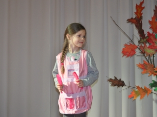 Uśmiechnięta dziewczynka w stroju fryzjerki na scenie 