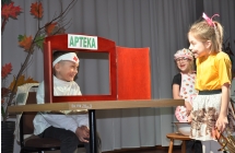 Uśmiechnięta dziewczynka  i chłopczyk w stroju aptekarza na scenie 