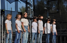 Kilkanaście dziewczynek śpiewających do mikrofonów na statywach 