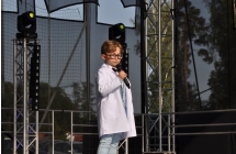 Chłopczyk w stroju lekarza na scenie. Wykonuje piosenkę 