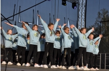 Kilkanaście młodych tancerek prezentujących układ taneczny na scenie 