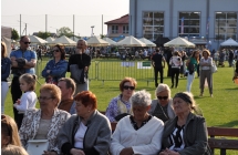 Widzowie części artystycznej na tle wesołego miasteczka 