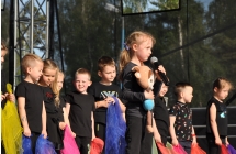 Dziewczynka śpiewająca na scenie w towarzystwie innych dzieci 
