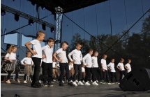 Tancerze na scenie w dwóch rzędach. W pierwszym chłopcy, w drugim dziewczynki 