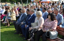 Elegancko ubrani mężczyźni i kobiety siedzący na ławce przed sceną 
