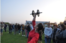 Kobieta podnosząca ciężar w zawodach sportowych. W tle liczna publiczność 