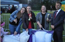 Trzy kobiety - laureatki konkurencji sportowej wraz z elegancko ubranym mężczyzną 