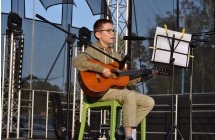 Młody chłopiec grający na gitarze i śpiewający piosenkę 