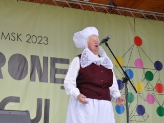 Kobieta w ludowym stroju śpiewająca na scenie 