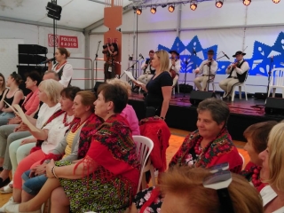 Kilkudziesięcioro słuchaczy i biorących udział w warsztatach z zespołem góralskim pod namiotem