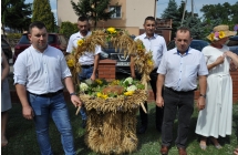 Czterech mężczyzn i kobieta przy wieńcu dożynkowym 