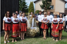 Kilkunastoosobowa delegacja wieńcowa. Są w niej kobiety ubrane na ludowo 