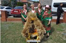 Cztery kobiety w ludowych strojach przy wieńcu dożynkowym 