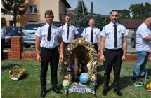 Czworo mężczyzn w strojach galowych z wieńcem dożynkowym 