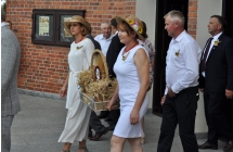 Eleganckie kobiety niosące wieniec dozynkowy pod kościołem 