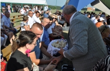 Mężczyzna częstujący chlebem gości dożynkowych 