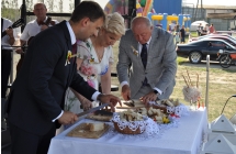Dwoje mężczyzn i kobieta podczas uroczystego krojenia chleba dożynkowego 