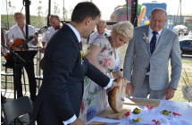 Dwoje mężczyzn i kobieta podczas krojenia chleba 