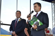 Dwoje mężczyzn na scenie, jeden mówi do mikrofonu