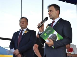 Dwoje mężczyzn na scenie, jeden mówi do mikrofonu