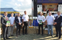 Siedmioro mężczyzn pozujących do zdjęcia z wieńcem dożynkowym 