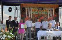 Siedmioro mężczyzn i dwie kobiety na scenie. Wszyscy odświętnie ubrani 