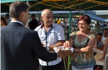 Mężczyzna częstujący małżeństwo chlebem dożynkowym 