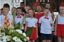 Kilkunastu dzieci śpiewających na scenie 