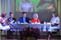 Cztery  kobiety i mężczyzna siedzący przy stole. 