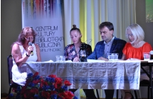 Trzy kobiety i mężczyzna siedzący przy stole na scenie 
