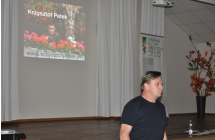 Mężczyzna na tle sceny na której wyświetlane jest jego zdjęcie 