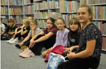 Dzieci siedzące na tle książek w bibliotece 