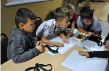 Grupa dzieci pracujących przy stole nad rozwiązaniami zagadek detektywistycznych 