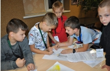 Pięcioro chłopców przy stole rozwiązujących zagadki 