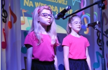 Dwie dziewczynki na scenie. Wykonują utwór muzyczny 