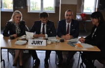 Dwójka mężczyzn i dwie kobiety siedzące przy stole. Na stole napis - jury 