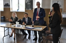 Dwie kobiety i dwoje mężczyzn. Jedna z kobiet stoi i mówi do mikrofonu 