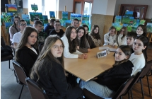 Kilkudziesięcioro uczniów przy siedzących przy stole 