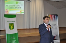 Mężczyzna mówiący do mikrofonu. W tle banery z napisem - centrum kultury i gmina malanów