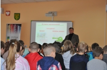Mężczyzna stoi przed dużą grupą siedzących dzieci