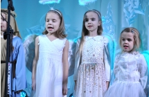 Trzy dziewczynki przebrane za aniołki stojące na scenie 