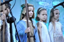 Trzy dziewczynki przebrane za aniołki i pastuszka stojący na scenie 