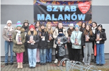 Kilkudziesięciu wolontariuszy WOŚP. Stoją przed budynkiem CKiBP w Malanowie. Za nimi szyld z napisem - SZTAB MALANÓW 
