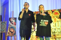 Kobieta i mężczyzna na scenie. Kobieta trzyma koszulke z logo WOŚP, mężczyzna mówi do mikrofonu 