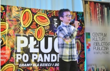 Chłopiec na scenie śpiewający utwór muzyczny 