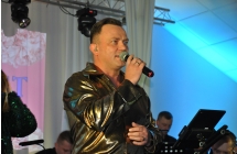 Mężczyzna w charakterystycznym stroju mówi do mikrofonu na scenie 